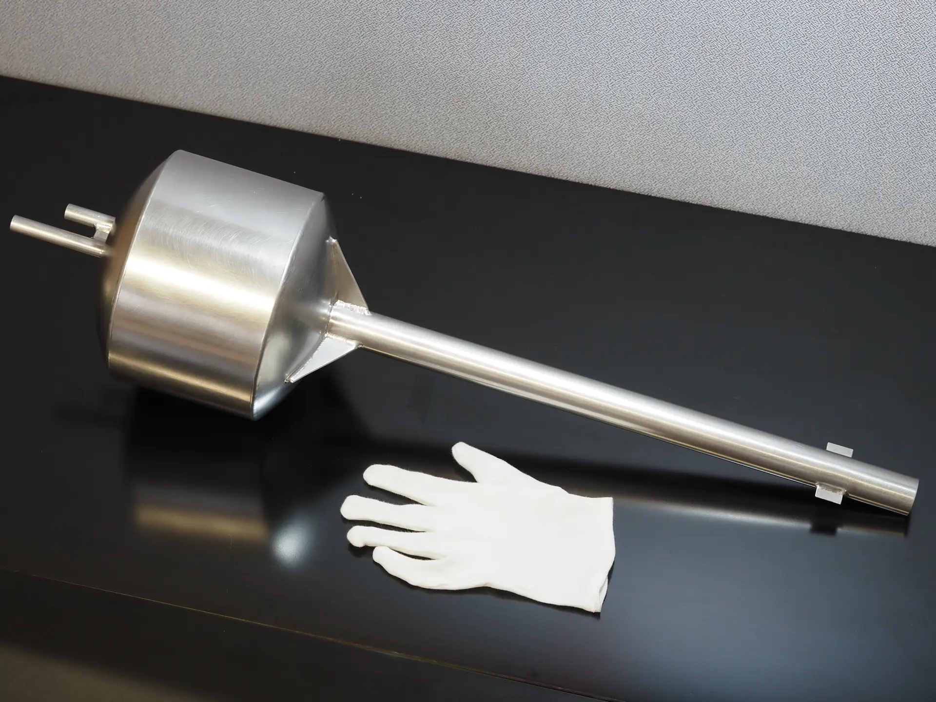 Großer Gießtiegel mit Griff im Größenvergleich zum Laborhandschuh.