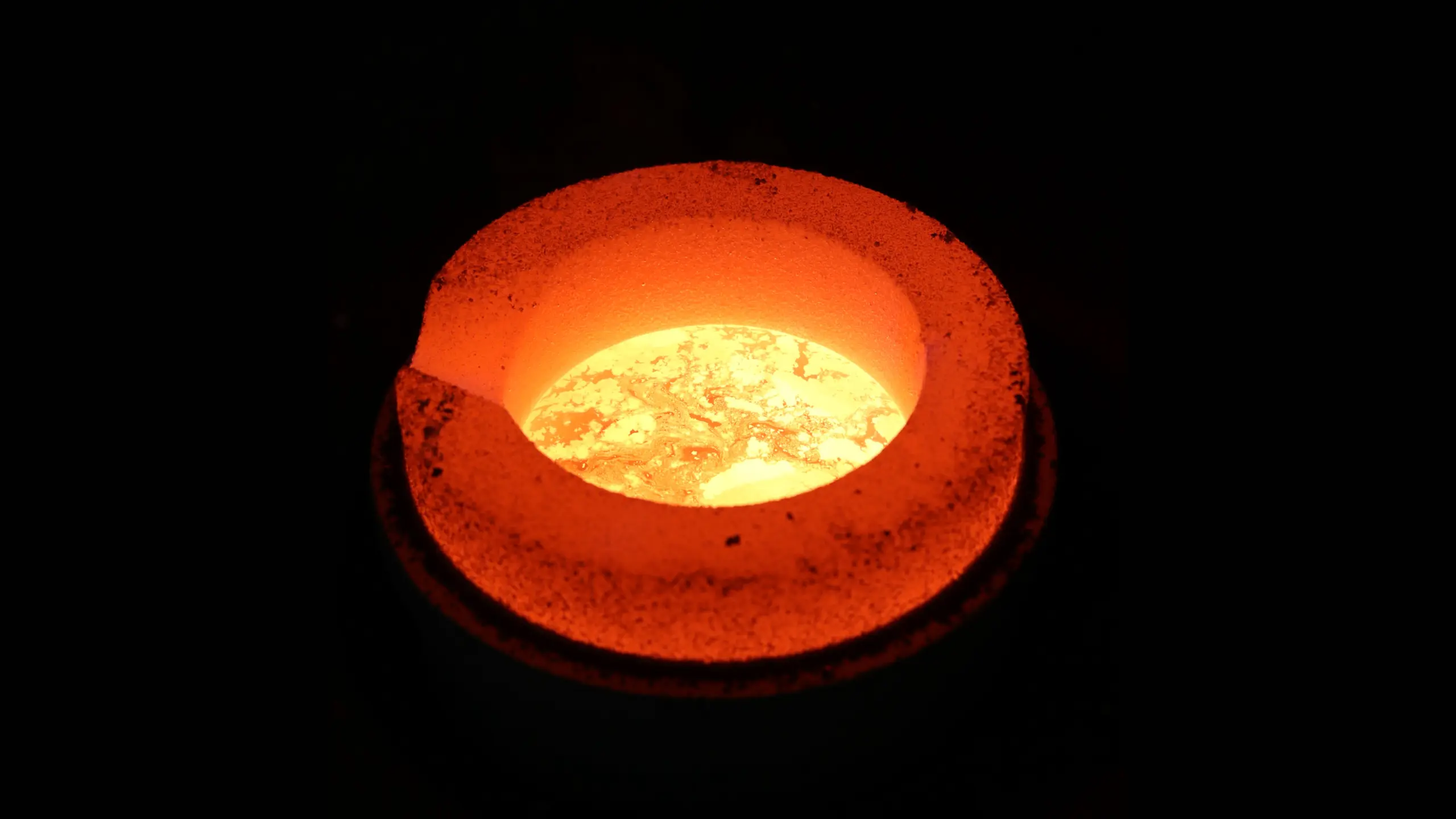 Glühende Edelmetallschmelze im Tiegel während des Einschmelzprozesses