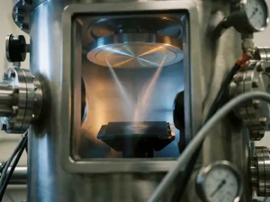 Silber-Gold-Legierungsscheibe in Vakuumkammer mit zwei konvergierenden Metallpartikelströmen auf dunklem Glassubstrat.
